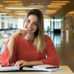 Portrait of Young female student working in the university library.